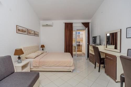 a bedroom with a bed and a desk and a couch at Vanila Apartmani in Sutomore