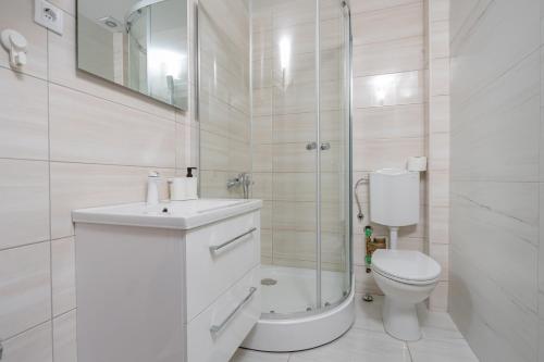 a white bathroom with a toilet and a shower at Vanila Apartmani in Sutomore