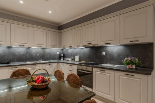 a kitchen with white cabinets and a table with a basket of fruit at Dionysis Elegant Cozy Apartment in Filiatra