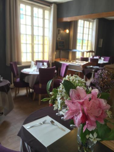 a vase of flowers on a table in a restaurant at Le Cheval Blanc in Jargeau