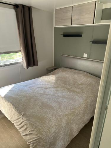 塞里尼昂Mobil Home SIBLU VALRAS PLAGE的卧室里有一张白色的床，还有一扇窗户