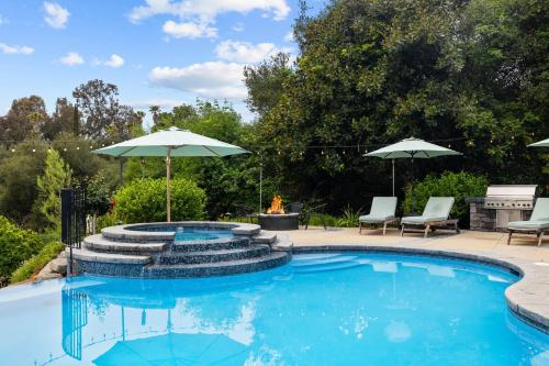 a pool with an umbrella and chairs and a fire place at Sprawling Escondido Estate Garden Pool Games ADU's in Escondido
