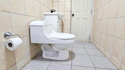 a white toilet in a bathroom with a roll of toilet paper at Lodge playa pupelde, Ancud in Mecura