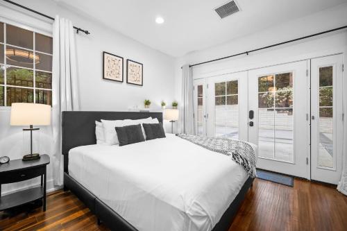 a bedroom with a large white bed and windows at Sprawling Escondido Estate Garden Pool Games ADU's in Escondido