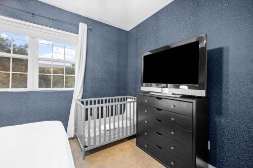 a room with a crib and a television on a dresser at Sprawling Escondido Estate Garden Pool Games ADU's in Escondido