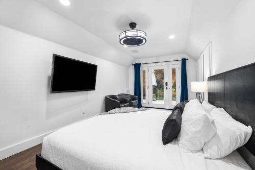a bedroom with a white bed and a tv at Sprawling Escondido Estate Garden Pool Games ADU's in Escondido
