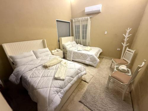 a hotel room with two beds and a chair at مفتاح الحياه in Banī Ghālib