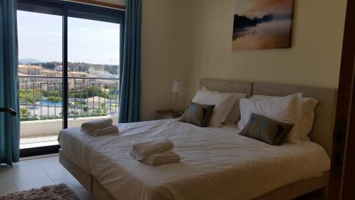 a bedroom with a large bed with a large window at Vista das Ondas Apartamento 205 B2 - Olhos de Agua in Albufeira