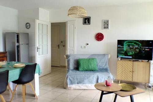 un salon avec un canapé bleu et une télévision dans l'établissement The 2 bedroom apartment with balcony - near park, à Toulon