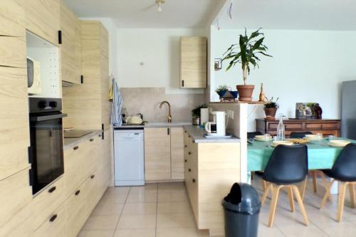 une cuisine avec des armoires en bois et une table et des chaises dans l'établissement The 2 bedroom apartment with balcony - near park, à Toulon