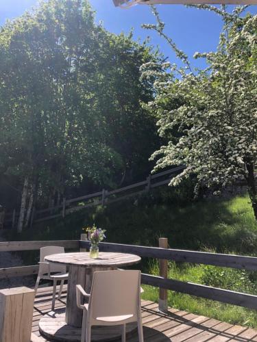 a patio with a table and chairs and trees at Gîte Le p'tit Chasseral in Maîche