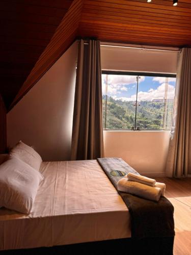 a bed in a room with a large window at VELINN Pousada Casa de Campos Mountain House in Campos do Jordão