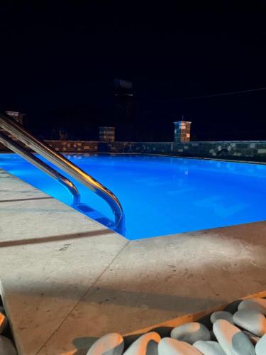 a large blue swimming pool at night at Mimani Stone House Roshnik in Roshnik