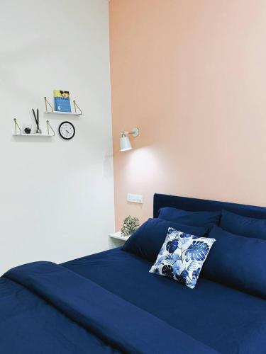 a blue bed with a pillow and a clock on the wall at Dhooni in Hithadhoo