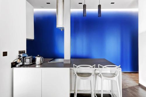 une cuisine avec deux chaises blanches et un mur bleu dans l'établissement appartement de Luxe haussmannien aux champs-elysees, à Paris