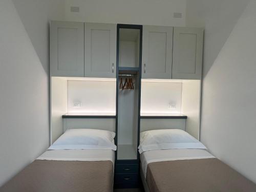 two beds in a small room with white cabinets at Perla D'Oriente - Affittacamere in Otranto