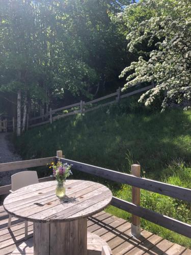 a wooden table with a vase of flowers on a deck at Gîte Le p'tit Chasseral in Maîche