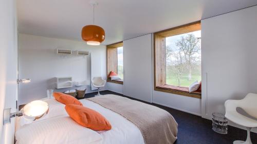 sypialnia z łóżkiem z pomarańczowymi poduszkami i oknem w obiekcie côté verger B&B w mieście Battice