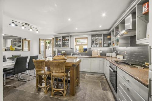 a kitchen with white cabinets and a table and chairs at Coach House in Bridgend