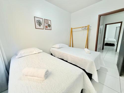 2 Betten in einem weißen Zimmer mit Spiegel in der Unterkunft Ap Conforto no Centro de Sinop in Sinop