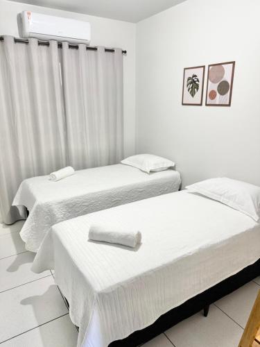 two beds in a room with white walls at Ap Conforto no Centro de Sinop in Sinop