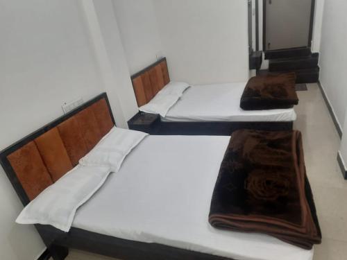 three beds in a room with white sheets and a blanket at annpurna home stay in Ujjain