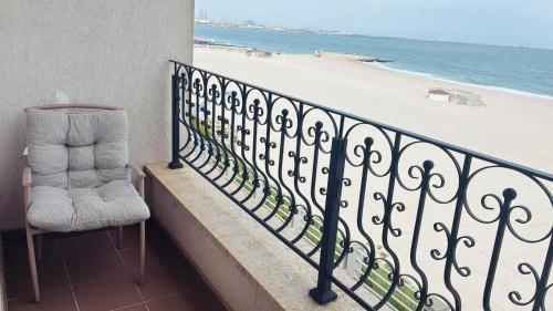 a chair sitting on a balcony overlooking the beach at ElStefanino House in Eforie Nord