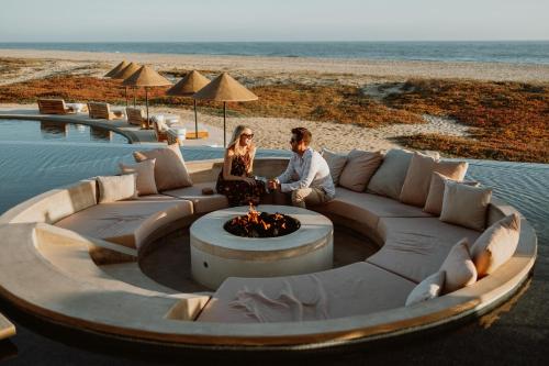 a man and woman sitting on a couch next to the beach at Kimpton Mas Olas Resort and Spa in Todos Santos