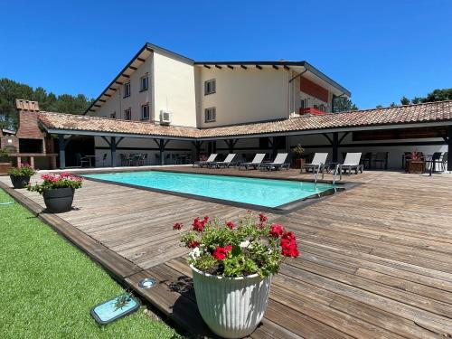 - une piscine fleurie sur une terrasse en bois dans l'établissement Hôtel Paris Madrid, à Lesperon