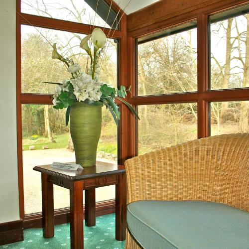a vase with flowers on a table next to a window at Ellington Lodge at The Concorde in Eastleigh