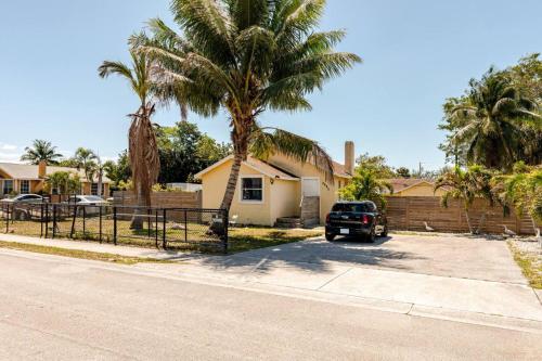a car parked in front of a house with palm trees at Beautiful home in West Palm - 5 min to Airport in West Palm Beach