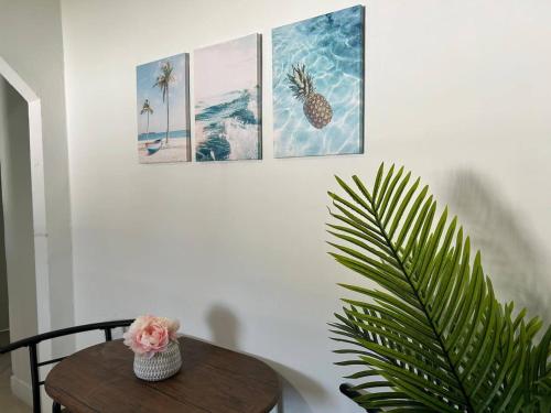 a table with a plant and four pictures on the wall at Beautiful home in West Palm - 5 min to Airport in West Palm Beach