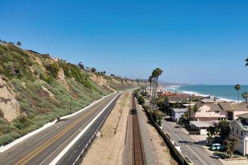 an empty highway next to the ocean with palm trees at Private beach toes on the Sand Waterworld in Dana Point