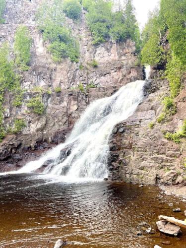 a waterfall on the side of a rocky mountain at Moose Mtn Retreat Ski in out Condo Pool Hot Tub Fire Pits in Lutsen