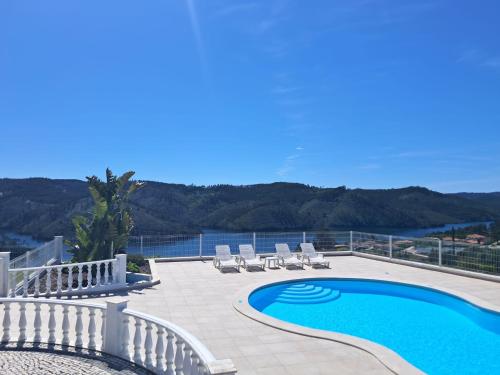 a swimming pool with chairs and a view of the water at Lago Azul Villas in Ferreira do Zêzere