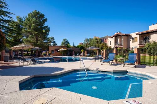 a swimming pool with blue chairs and umbrellas at Serenity Now in Beautiful Sedona - 3 BR 2 BA in Sedona