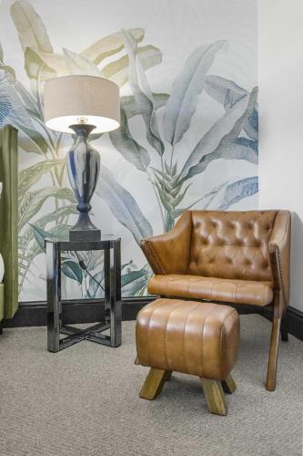 a brown leather chair and a table with a lamp at Coach House in Bridgend