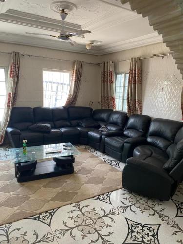 a living room with a black leather couch and a table at Keur Teranga in Serekunda