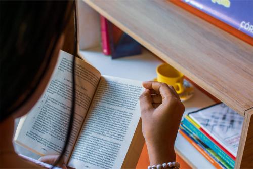 a person holding a book in a book shelf at Cabañas Los Venaos in San Bernardo del Viento