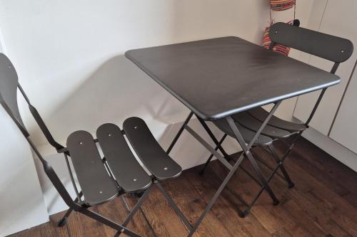 une table noire et deux chaises à côté d'une table dans l'établissement Nice 2 rooms in the Quartier Charonne Paris, à Paris