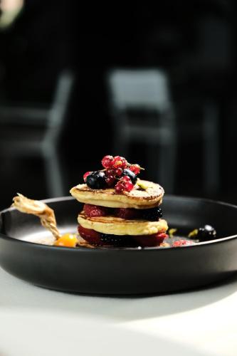 a stack of pancakes with berries on a plate at Joelle Premium Hotel in Sarandë