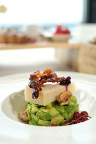 a white plate with a piece of cheese and fruit at Joelle Premium Hotel in Sarandë