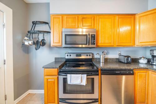 a kitchen with a stove and a microwave at Cozy Brick-Short North Condo - (fenced yard) - OSU in Milo