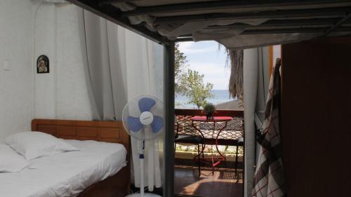 a bedroom with a bed and a balcony with a table at StudioAretiCom Studio to rent in FRONT the lovely SEA fully equipped plagiastudioseu in Nea Plagia