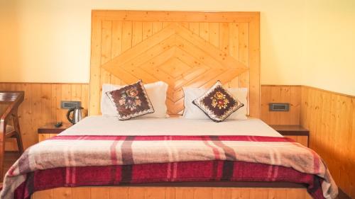 a bedroom with a large bed with a wooden headboard at Kanwar Villa Bir in Chauntrā