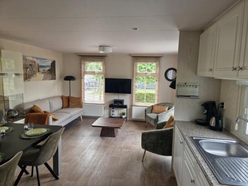 a kitchen and living room with a couch and a table at Chalet de Zeeuwse Zon in Baarland