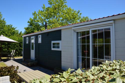 a black and white tiny house with a patio at Chalet de Zeeuwse Zon in Baarland