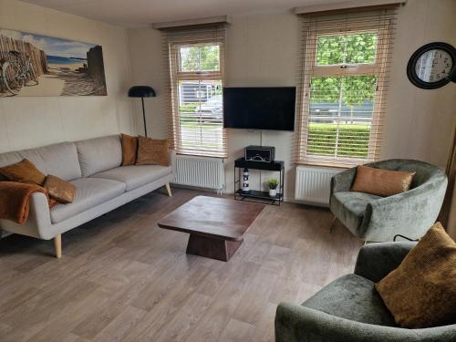 a living room with a couch and two chairs and a table at Chalet de Zeeuwse Zon in Baarland