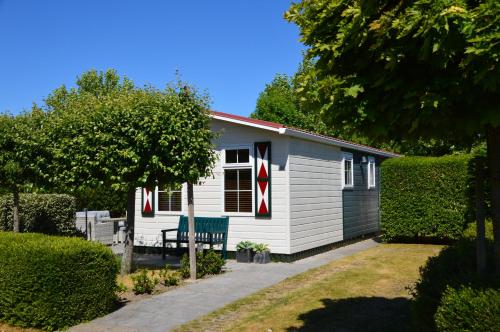 a small white cottage with a bench in the yard at Chalet de Zeeuwse Zon in Baarland