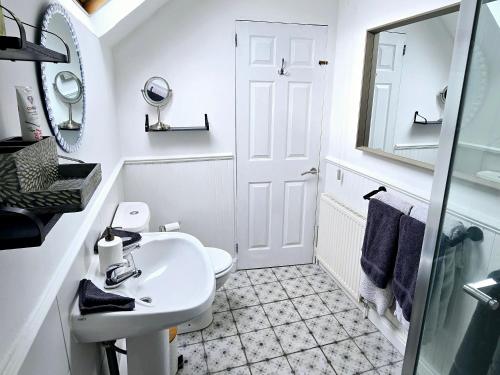 ein weißes Badezimmer mit Waschbecken und Spiegel in der Unterkunft Gorgeous Two Bedroom Cottage, Pet Friendly! in Snainton